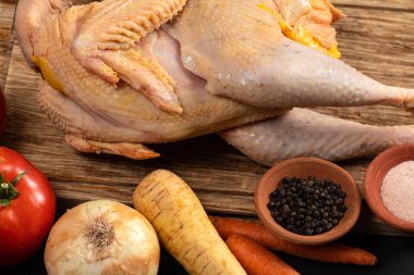 Domatesli, soğanlı, havuçlu, havuçlu, karabiberli ve tuzlu çiftlik tavuğu köy ahşabının üzerinde bulunur. Tavuk çorbası pişirmek için taze çiğ tavuk ve sebze..