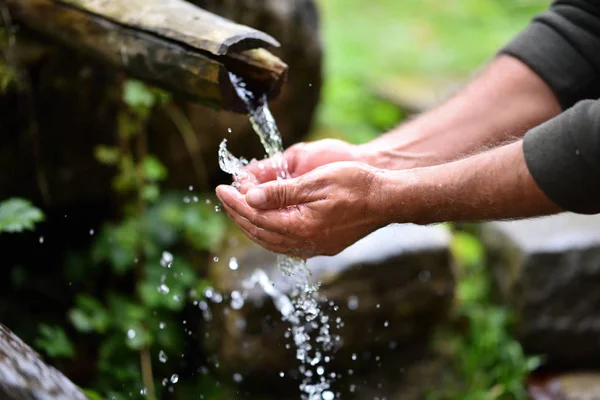 man washing hands in fresh, cold, potable water of mountain spring