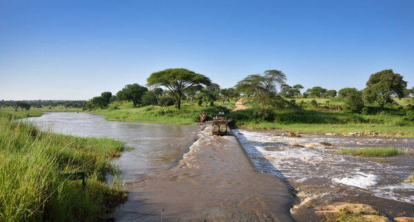 road in the wilderness crossing river in natural park, safari trip in Tanzania, Africa