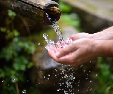 Adam dağ baharın taze, soğuk, içilebilir su el yıkama