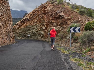 Trail running woman on mountain nature adventure training on rocky volcanic rocks path in mountains in high altitude in Gran Canaria, Spain