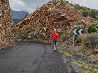 Trail running woman on mountain nature adventure training on rocky volcanic rocks path in mountains in high altitude in Gran Canaria, Spain