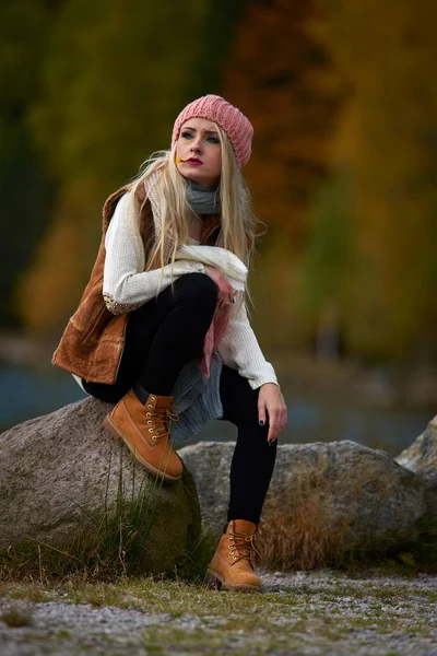 young pretty woman outdoor in fall sitting by the lake