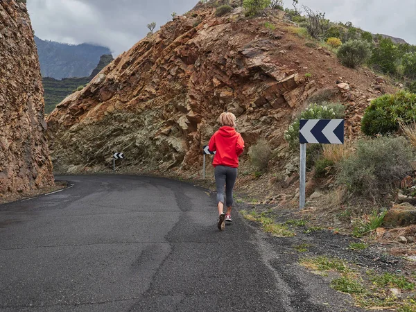 Trail running woman on mountain nature adventure training on rocky volcanic rocks path in mountains in high altitude in Gran Canaria, Spain