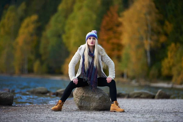 young pretty woman outdoor in fall sitting by the lake