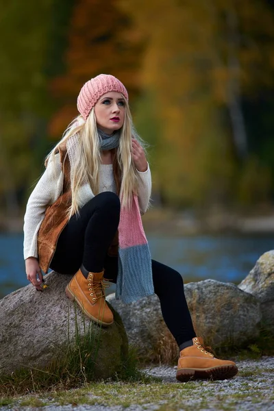 young pretty woman outdoor in fall sitting by the lake