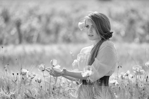 Young beautiful woman on cereal field with poppies in summer - black and white image
