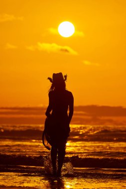 genç bir kadın silueti sahilde günbatımı yaz ışık