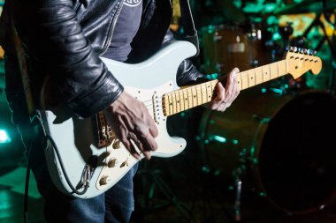 Gitarist konserde gitar tutuyor.