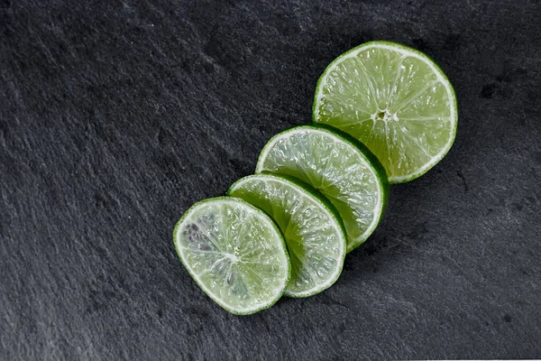 Lime background. The slices of lime on a stone base. On a stone table. Free space for text . The view from the top