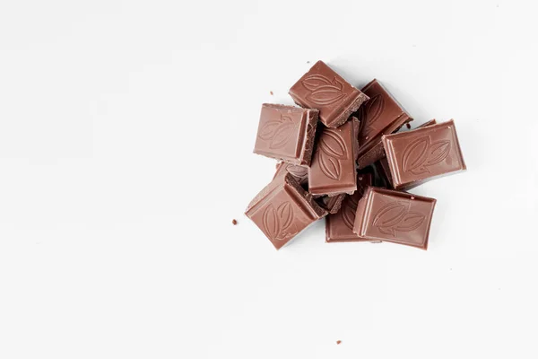 Milk chocolate pieces isolated on white background from top view, close up a chocolate bar isolated on white background