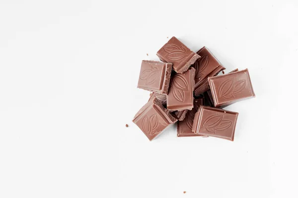 Milk chocolate pieces isolated on white background from top view, close up a chocolate bar isolated on white background