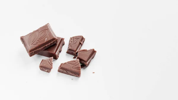 하얀 배경 위에서 분리 된 밀크 초콜릿 조각들이 하얀 배경 위에 분리되어 초콜릿 바를 닫는다 — 스톡 사진