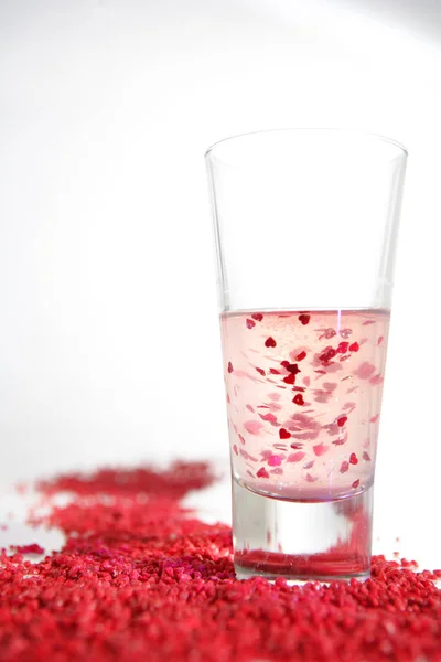 Glas Met Hartjes Water Rood Poeder Witte Ondergrond — Stockfoto