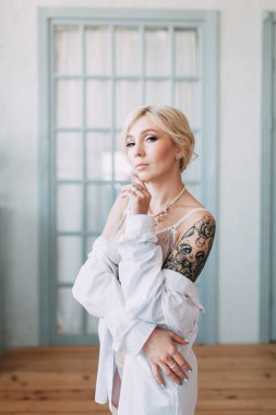 Bir güzel keten elbise ve boudoir stüdyoda gelinin şarj olur. Seksi kız çıplak bir vücut ile bir gömlek. Saç ve makyaj gelin. Düğün öncesi fotoğraf çekimi