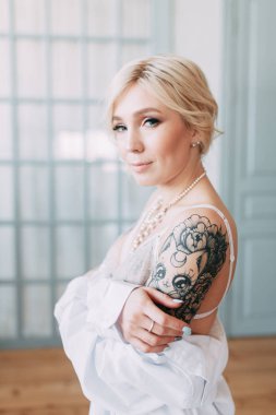 Bir güzel keten elbise ve boudoir stüdyoda gelinin şarj olur. Seksi kız çıplak bir vücut ile bir gömlek. Saç ve makyaj gelin. Düğün öncesi fotoğraf çekimi