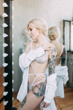 Bir güzel keten elbise ve boudoir stüdyoda gelinin şarj olur. Seksi kız çıplak bir vücut ile bir gömlek. Saç ve makyaj gelin. Düğün öncesi fotoğraf çekimi