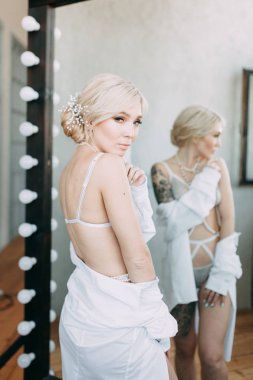 Bir güzel keten elbise ve boudoir stüdyoda gelinin şarj olur. Seksi kız çıplak bir vücut ile bir gömlek. Saç ve makyaj gelin. Düğün öncesi fotoğraf çekimi