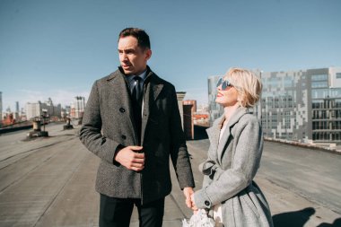 Sokaktaki binanın çatısında çekim düğün öncesi. Gülme, sarılma ve çalışan mutlu çift. Gülümse ve halkı yakışıklı görünüyor. günbatımı evleri ve sokakları