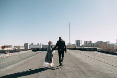 Sokaktaki binanın çatısında çekim düğün öncesi. Gülme, sarılma ve çalışan mutlu çift. Gülümse ve halkı yakışıklı görünüyor. günbatımı evleri ve sokakları