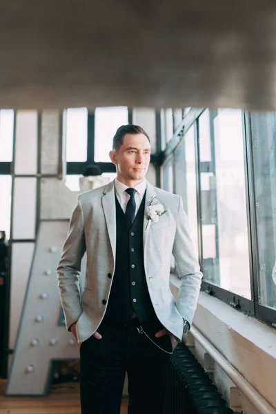 Gathering of a beautiful groom, waiting for the bride. Photo shoot in the interior Studio. Wedding in European style. Handsome man in a jacket and trousers