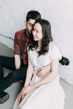 bir fotoğraf karizmatik çifte Avrupa tarzında vur. Sarılma ve birbirine bakarak gülümsüyordu. Geçici belgili tanımlık bakmak ve ışık havadar elbise kız. Studio loft ve güzel bir kız
