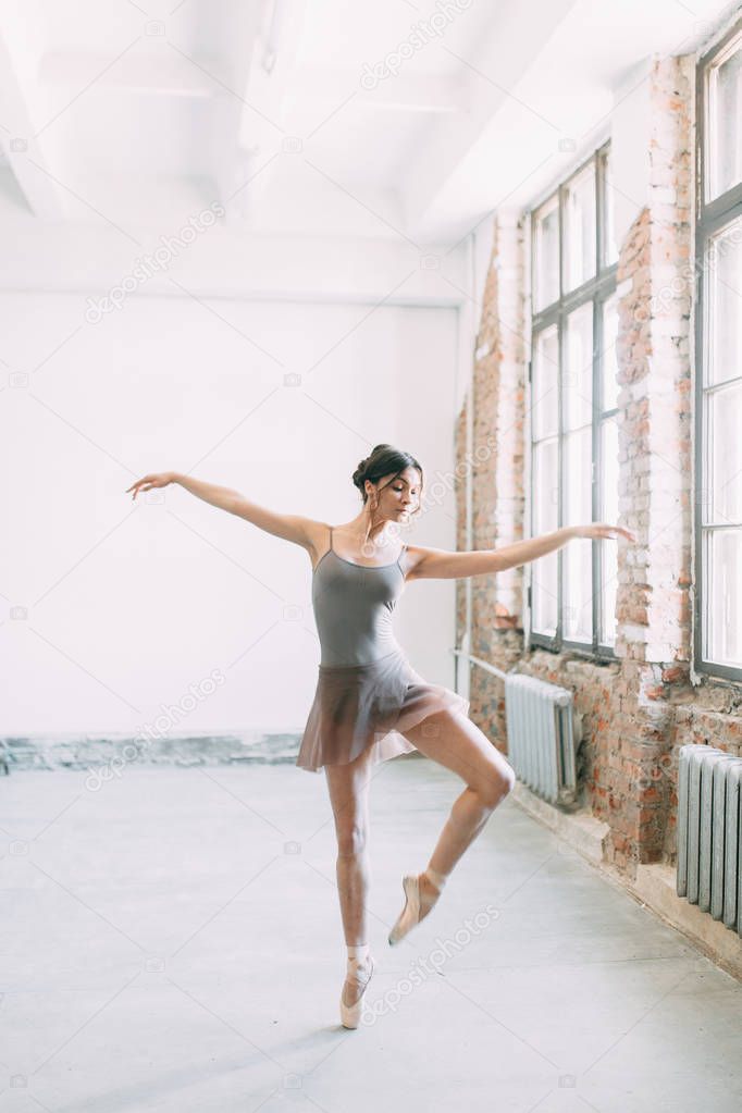 A young ballerina is getting ready, stretched and dancing. Poses in ballet. Photo shoot in the loft Studio. Russian Ballerina at the bench. ballet flats and dance dress