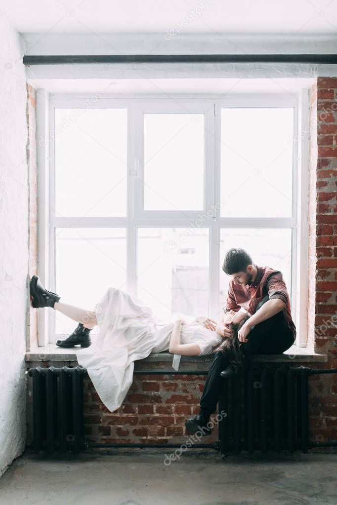 charismatic couple at a photo shoot in European style. Hugging and smiling looking at each other. The casual look and the light airy dress of the girl. the loft Studio, and a beautiful girl
