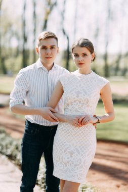 Güzel genç çift parkta güneşli bir günde, sevgi dolu ve mutlu. Yürümek ve birlikte gülmek. Doğada çekim düğün öncesi. Zarif bir tarzda giysi gibi ünlüler