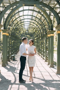 Güzel genç çift parkta güneşli bir günde, sevgi dolu ve mutlu. Yürümek ve birlikte gülmek. Doğada çekim düğün öncesi. Zarif bir tarzda giysi gibi ünlüler