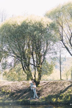 Güzel genç çift parkta güneşli bir günde, sevgi dolu ve mutlu. Yürümek ve köpekle gülmek. Doğada çekim düğün öncesi. Casual tarzda işleme giyim ve Avrupa