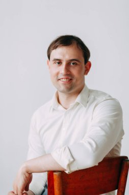 Doğal ışık ile yakışıklı genç damat Studio. Avrupa tarzı düğün fotoğraf çekimi. Adam oturan kat ve ayakta, yalan makinesini holding üzerinde gülümseyen