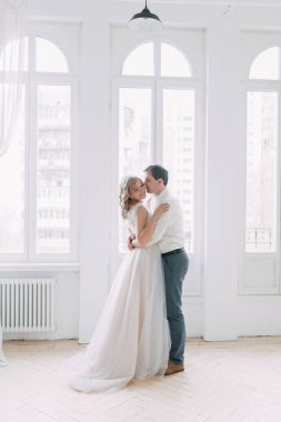 Güzel çift düğün fotoğraf çekimi. Studio loft Avrupa tarzında, parlak ve büyük pencereler ile. Sevgi dolu insanlar mutlu yüzler ile. Gelin buketi ve şık dekoratif.