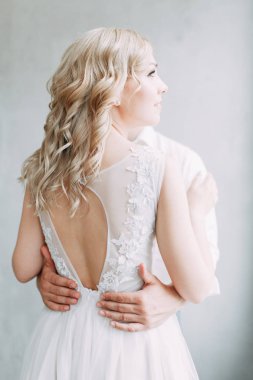 Parlak bir stüdyoda gelinlik içinde güzel bir gelin. Avrupa usulü düğün. Dekor ve buket elinde. Genç kız ayakta, oturuyor ve poz veriyor.