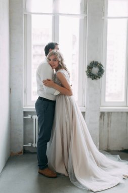 Güzel çift düğün fotoğraf çekimi. Studio loft Avrupa tarzında, parlak ve büyük pencereler ile. Sevgi dolu insanlar mutlu yüzler ile. Gelin buketi ve şık dekoratif.