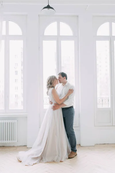 美丽的情侣在婚礼照片拍摄 阁楼工作室欧式风格 有大窗户 喜欢有幸福面孔的人 新娘花束和时尚装饰 — 图库照片