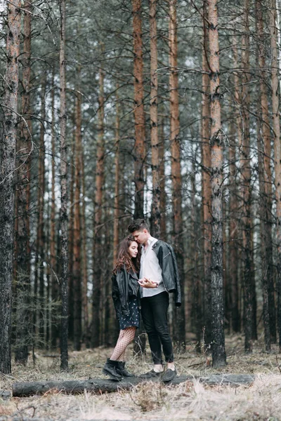 Young stylish couple in the forest, running around the Park and laughing. Modern people on a walk. Beautiful girl with tattoos. Loving young man and girl. mountain Park with pine forest