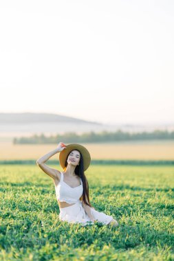 Bir şapka ve yaz elbise, alanın üzerinde yürüyen kız. Gülümseyen ve gülüyor, orman ve doğa güzel gün batımı. Beyaz elbise ve çavdar, alanları eğimli. Mutlu traveler, yaşam biçimi.