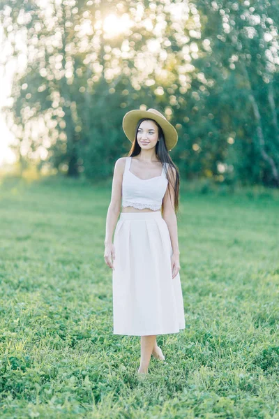 女孩走在田野上 在帽子和夏季礼服 微笑和欢笑 美丽的日落在森林和自然 白色礼服和黑麦 快乐的旅行者 生活方式 — 图库照片
