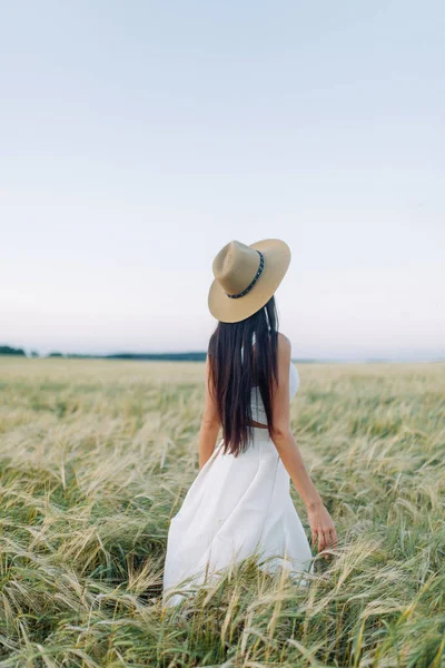 帽子と夏のドレスを着て フィールド上を歩く少女 笑顔し笑い 森林と自然の中の美しい夕日 白いドレスとライ 傾斜フィールド 幸せな旅行者 ライフ スタイル — ストック写真