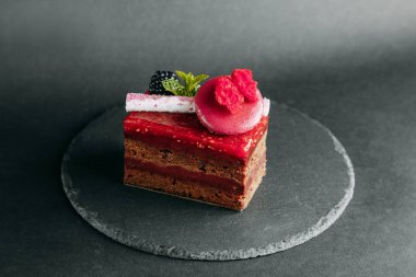 Berry kek bir siyah arka plan, yazarın tatlılar ve hizmet taş. Çikolata, çilek ve krema. Tasarım için Web sitesi