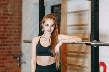Spor kız top ve spor salonunda dinlenme ilgilenir. Makineleri için sonraki ayakta ve gülümseyen.