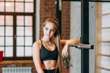 Spor kız top ve spor salonunda dinlenme ilgilenir. Makineleri için sonraki ayakta ve gülümseyen.