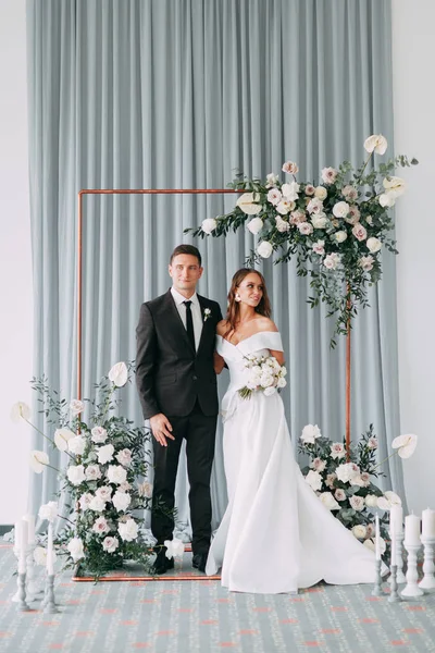 Stylish European wedding ceremony. The bride and groom are surrounded by guests. Arch and decor of fresh flowers.