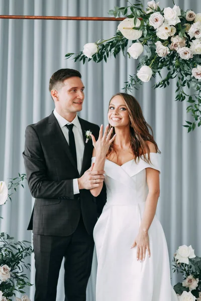 Stylish European wedding ceremony. The bride and groom are surrounded by guests. Arch and decor of fresh flowers.