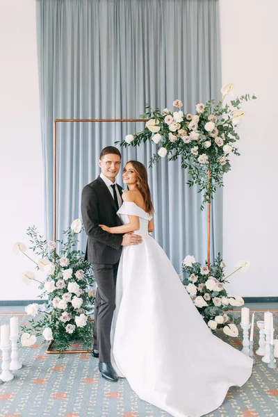 Stylish European wedding ceremony. The bride and groom are surrounded by guests. Arch and decor of fresh flowers.