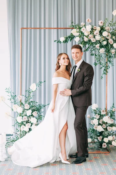 Stylish European wedding ceremony. The bride and groom are surrounded by guests. Arch and decor of fresh flowers.