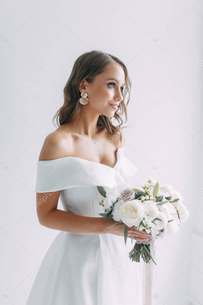 A concept wedding, contemporary European bride. Bouquet of flowers, fees in the interior Studio. Ideas for a minimalist wedding, white color