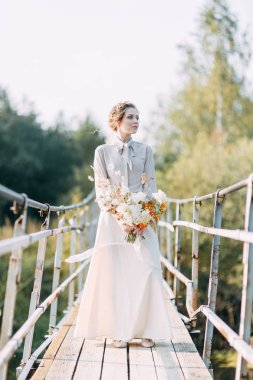 Çiçek ve dekorla düğün kemerinin önünde güzel bir gelin. Buket ellerde ve detaylarda. Kız mutlu, gülümsüyor ve dans ediyor. Modern tarzda bir gelinlik hayal et.