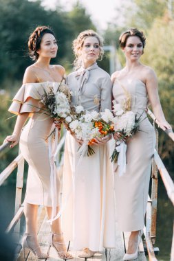 Çiçek ve dekorla düğün kemerinin önünde güzel bir gelin. Buket ellerde ve detaylarda. Kız mutlu, gülümsüyor ve dans ediyor. Modern tarzda bir gelinlik hayal et.